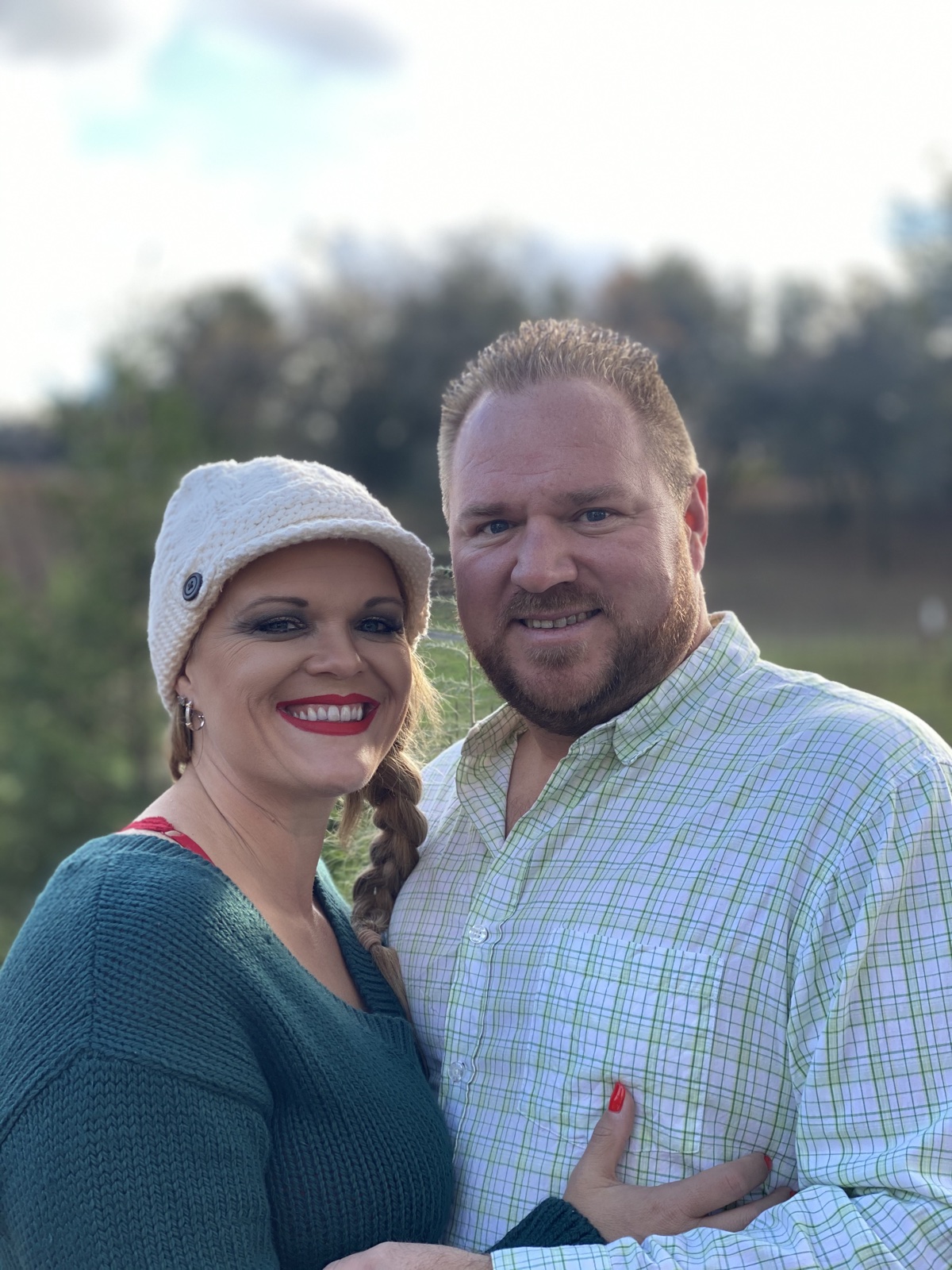 Mike and Kristie Clack standing together outdoors at golden hour, soft-focus Sierra Foothills landscape behind them